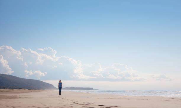 Backpacker female sitting on the Patara sand dunes beach enjoying the windy Mediterranean Sea during Lycian Way trekking walk. Famous Likya Yolu Turkish route. Active people vacation concept image