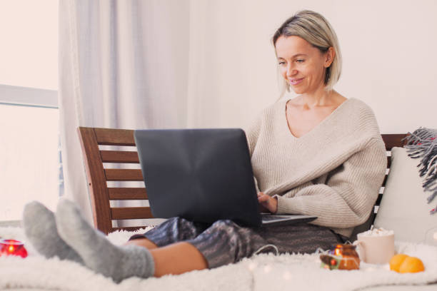 istock Happy middle aged woman using her laptop on the sofa at home 1368054464