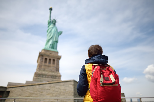 Tourist is traveling to island of liberty. Woman with backpack is on the background of the statue of liberty. New york, USA. Sightseeing of usa.