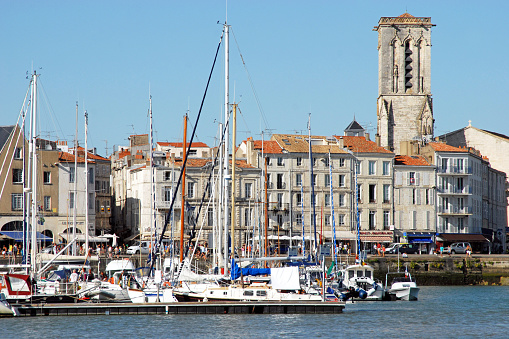 Marina quayside and Saint Saviour church at La Rochelle, Charente Maritime, France. La Rochelle is an ancient medieval coastal town on the Bay of Biscay Atlantic coastline full of Renaissance architecture and numerous stone arches that join half timbered houses in the narrow streets and is now the capital of the region