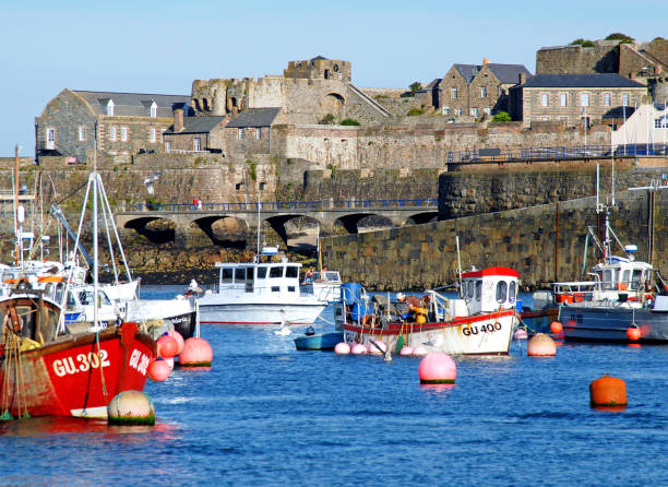 Alderney inner harbour and fort, Alderney Channel Island, UK. Commercial fishing boats and recreational pleasure craft moored in the harbour. Alderney is the third largest of the Channel Islands under the bailiwick of Guernsey but a British Crown dependency.