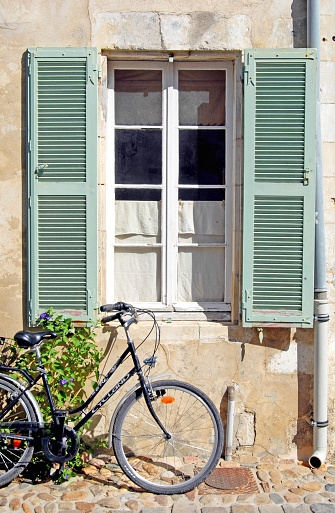 Bicycle and shuttered window detail on quayside house, Sauzon harbour, La Belle Ile, Morbihan, France. Sauzon is one of the main ports on the island and a tourist attraction with its beautiful architecture and tidal basin marina that attracts recreational sailors and fishing boats alike