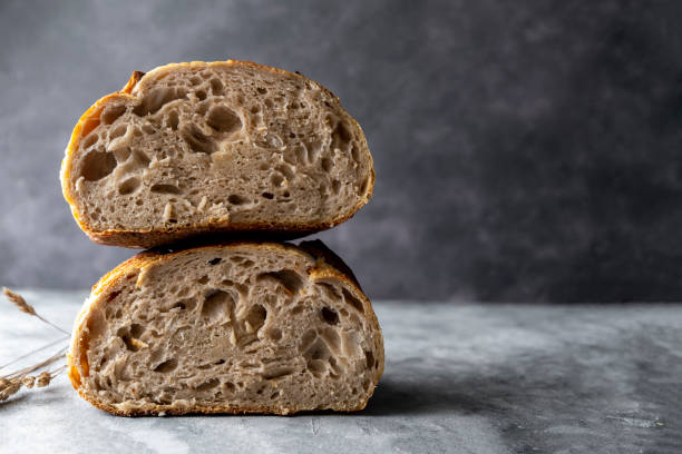 Sourdough artisan homemade bread sliced in halfs on dark background. Copy space Sourdough artisan homemade bread sliced in halfs, dark background, copy space yeast starter stock pictures, royalty-free photos & images