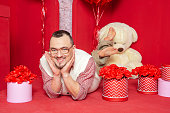 Funny happy bearded retro style man lying down near gift boxes and big teddy bear for Valentine day