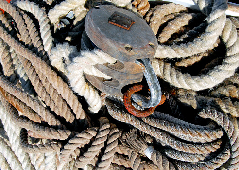 Old blocks, pulley blocks, tackle and ropes in a pile on the quayside waiting for use on a traditional sailing ship or tall ship, France