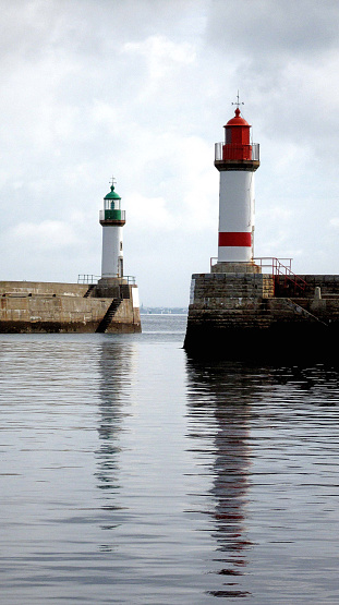 Lighthouses on the breakwater groynes of the harbour wall during calm water high tide at Ile de Groix, Brittany, France