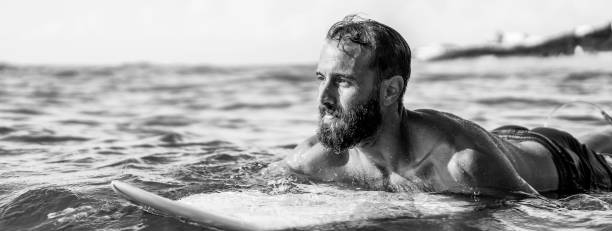 horizontal banner with young hipster man swimming on the surfboard into the sea water waiting for a big wave - guy having fun doing extreme sport - adventure and freedom concept doing water sports - hipster people surfing the net internet imagens e fotografias de stock