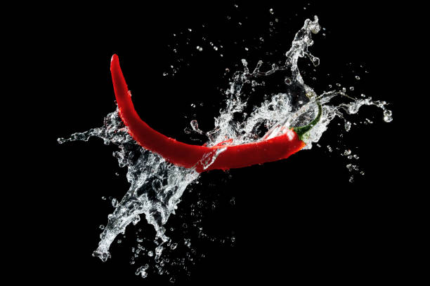 istock Red hot peppers in water splash over black background 1368064313