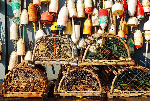 A pier in New England is populated with wooden vintage lobster traps and colorful lobster buoys from the local fishermen and trappers