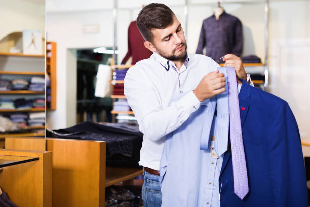 istock Handsome adult guy  choosing modern jacket in men store 1368065553