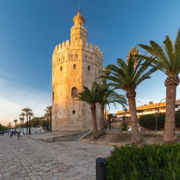 una vista de la icónica torre dorada en el muelle del río guadalquivir en sevilla en una tarde soleada - plaza de espana sevilla town square seville fotografías e imágenes de stock