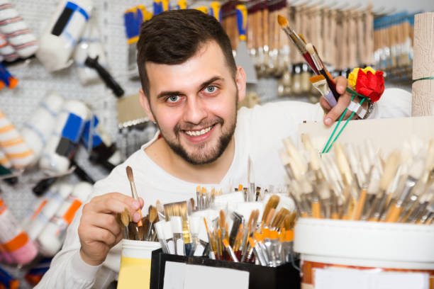 istock Young guy is deciding on best brush for painting and decorating 1368065659