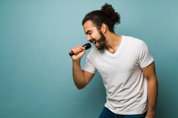 Cheerful man singing in a karaoke Having fun with karaoke. Amateur singer singing with a microphone and feeling excited singer stock pictures, royalty-free photos & images