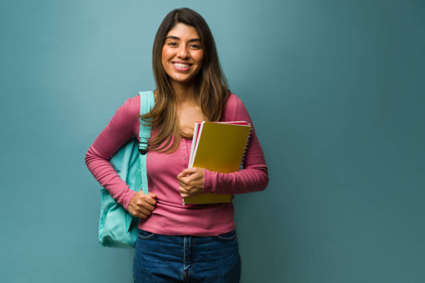 Beautiful woman going back to school Happy young woman wearing a backpack while carrying books and notebooks to college university student stock pictures, royalty-free photos & images