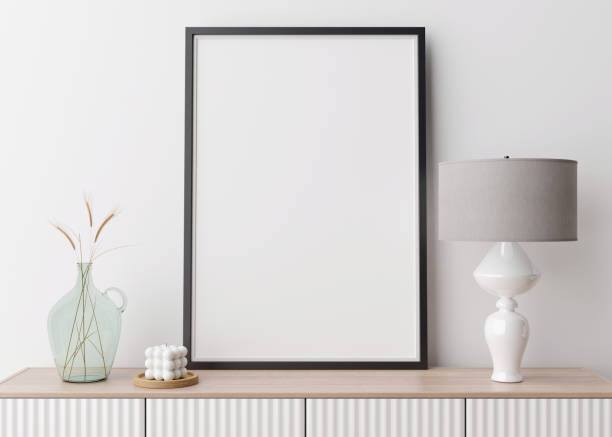 istock Empty vertical picture frame on white wall in modern living room. Mock up interior in contemporary style. Free space for picture, poster. Console, lamp, glass vase with grass, candle. 3D rendering. 1368070369