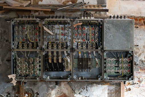 Old electric boxes with old cables distributing the electric current in a building. Broken and damaged technology. Ancient supply panel in an abandoned house with no people.