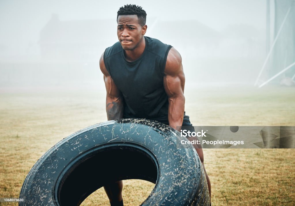 Shot of a muscular young man flipping a tyre while exercising outdoors Don't just flip past your goals Throwing Stock Photo