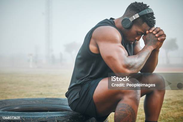 Shot Of A Muscular Young Man Wearing Headphones While Exercising Outdoors Stock Photo - Download Image Now