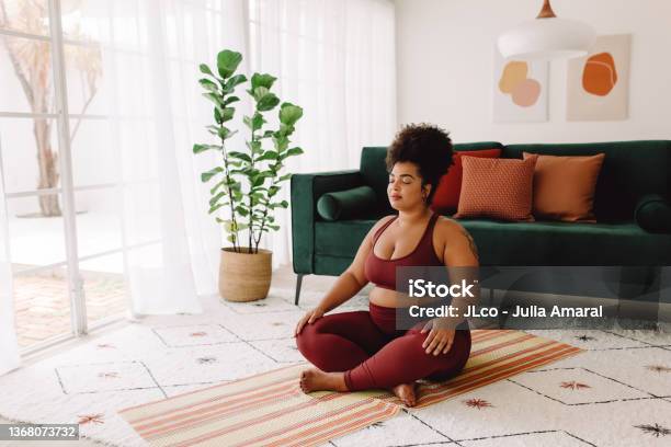 Plus Size Woman Practicing Meditation At Home Stock Photo - Download Image Now - Yoga, Wellbeing, Women