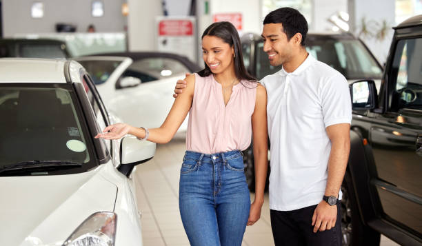 foto de una joven pareja mirando coches en un concesionario de coches - new automobile fotografías e imágenes de stock