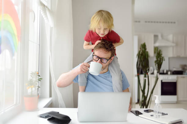 istock Man is working from home with laptop during quarantine. Home office and parenthood at same time. Exhausted parent with hyperactive child. 1368074782