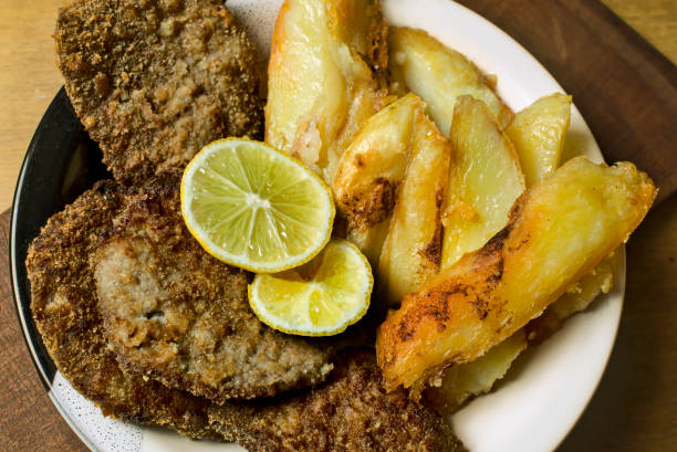 Milanese with roasted potatoes on plate top view