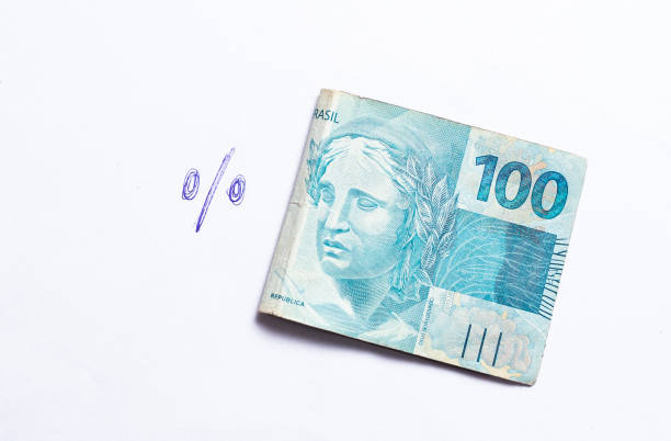 real - the brazilian currency and interest in the brazilian economy. a folded 100 reais banknote isolated on white background with the interest symbol next to it. - 100 percent fotos imagens e fotografias de stock