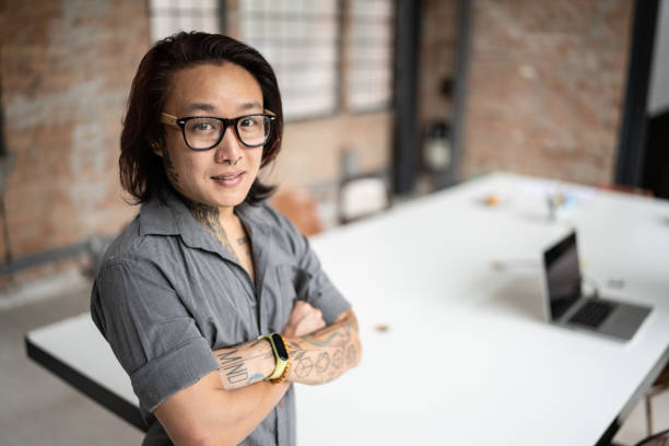 Portrait of a transgender male in an office Portrait of a confident transgender man in an office queer man facing camera stock pictures, royalty-free photos & images
