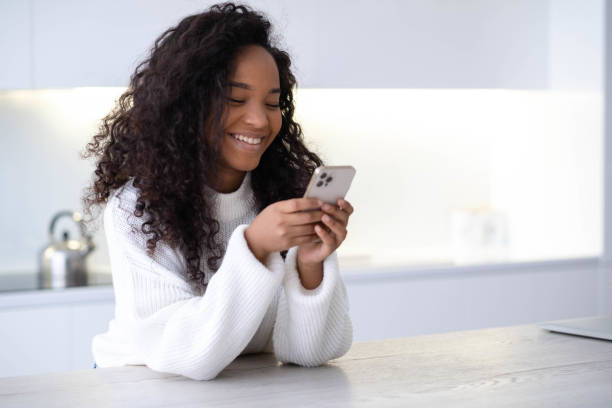 African American Girl using iPhone 12 smartphone pressing finger, reading social media internet, typing text or shopping online Mobile phone in two black hands 13.12.21 St.Petersburg Russia stock photo