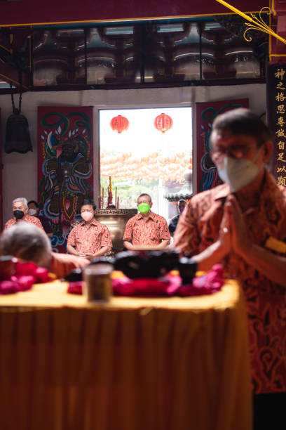 les visiteurs priant devant la table orange avec les offrandes - zen like women temple meditating photos et images de collection