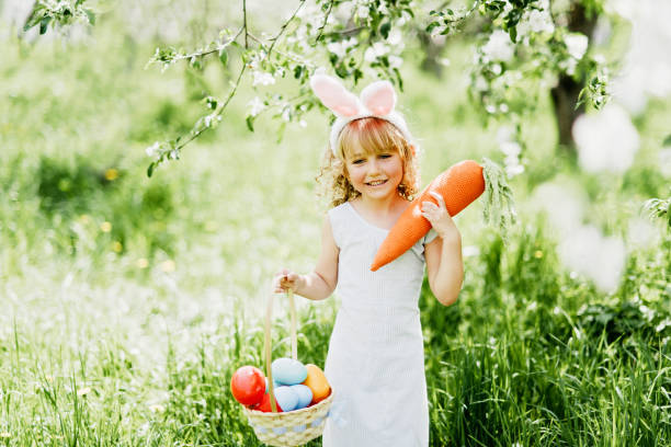 istock Cute funny girl with Easter eggs and bunny ears at garden. Easter concept. 1368076937