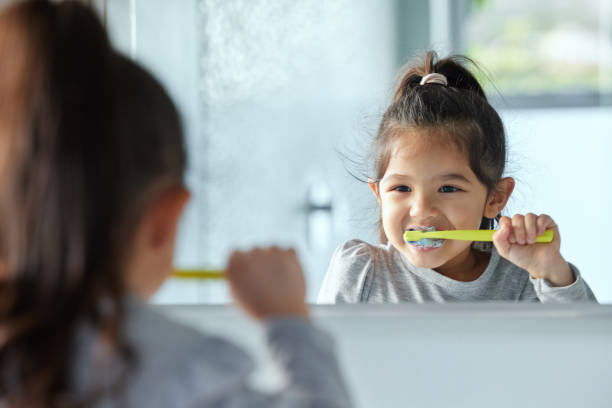 Shot of an adorable little girl brushing her teeth in a bathroom at home Getting into the routine of good hygiene Independence in Daily Activities:  in kids stock pictures, royalty-free photos & images