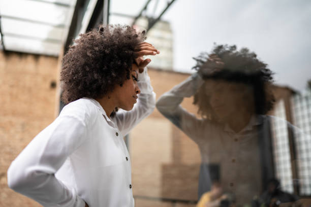 mujer de negocios preocupada que apoya la cabeza en una ventana - unemployment rate fotografías e imágenes de stock