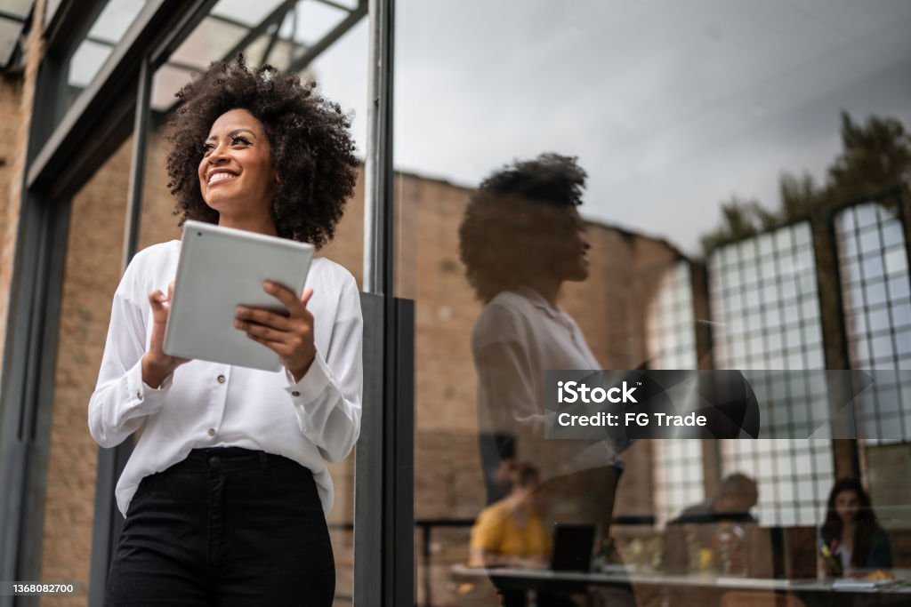 Businesswoman looking away and using digital tablet in an office Business Stock Photo