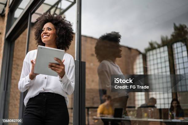 Businesswoman Looking Away And Using Digital Tablet In An Office Stock Photo - Download Image Now