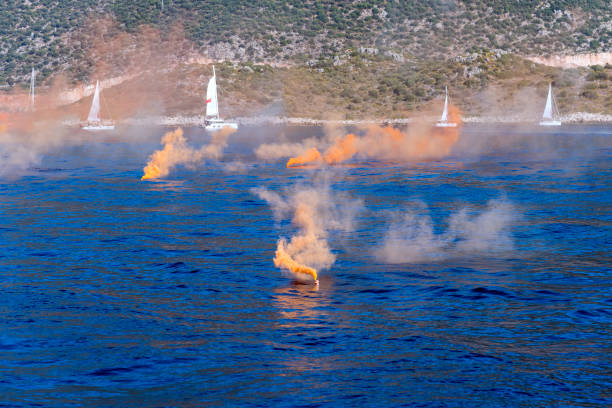 istock Orange colored smoke grenade with sail boats. Distress call 1368083014