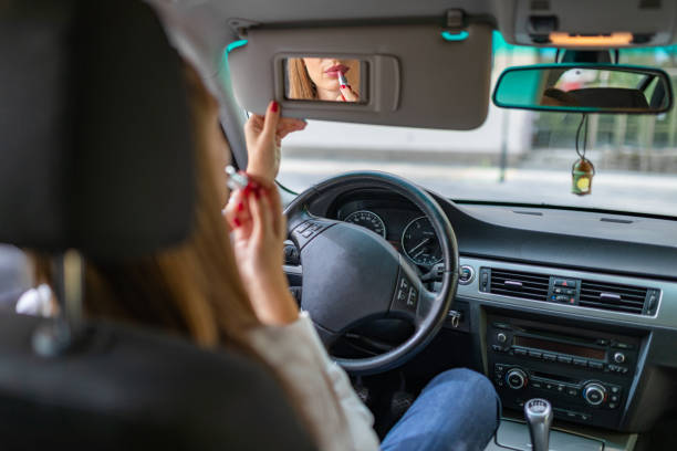 istock Young elegant woman looking in the car view mirror while applying lipstick 1368083093