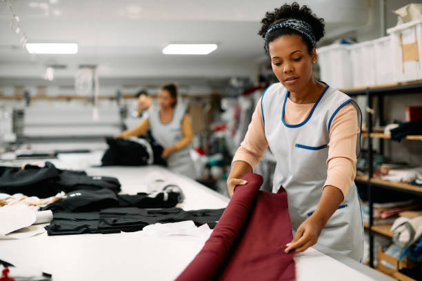 istock Young African American seamstress working with fabric at clothing design workshop. 1368083269