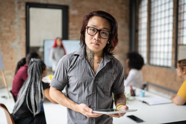 Portrait of a transgender man holding a digital tablet in the office Portrait of a transgender man holding a digital tablet in the office transgender person in office stock pictures, royalty-free photos & images