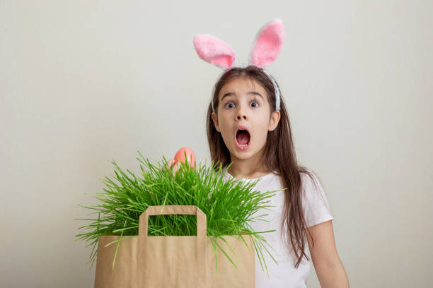 istock A surprised little girl with hare ears, holds a pink egg 1368085149