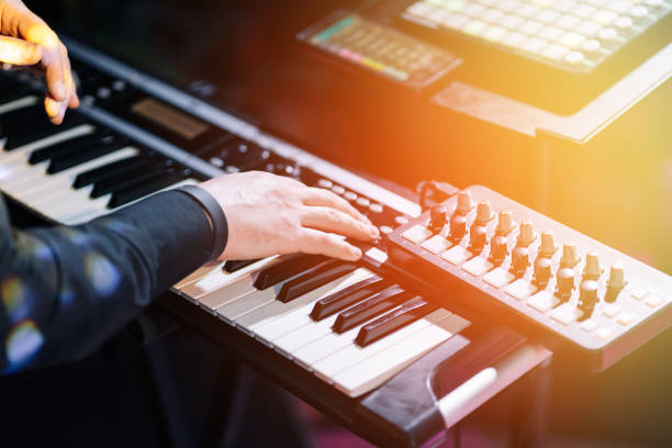 Close shooting of a keyboardist musician at work at a concert. Keyboardist play keyboard on stage. Selective focus Close shooting of a keyboardist musician at work at a concert. Keyboardist play keyboard on stage. Selective focus. synthesizer stock pictures, royalty-free photos & images