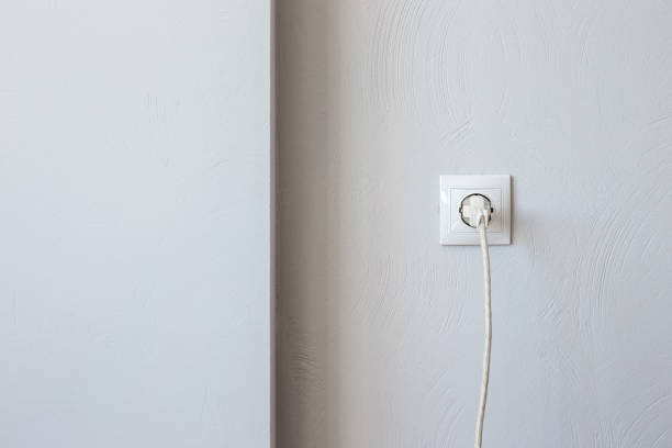 istock Plug with a cord in an electrical outlet against a gray wall with copy space. Electricity consumption 1368086533