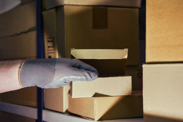 istock A man in gloves steals goods from a box in a warehouse. Problems with theft and security in the office 1368088575