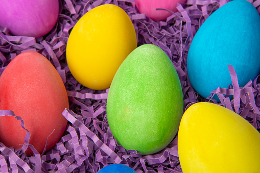 A close up of colorful Easter eggs in purple decorative paper.