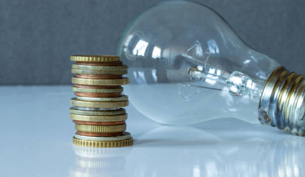 istock A stack of coins and a light bulb isolated on a white surface with a grey background 1368090890