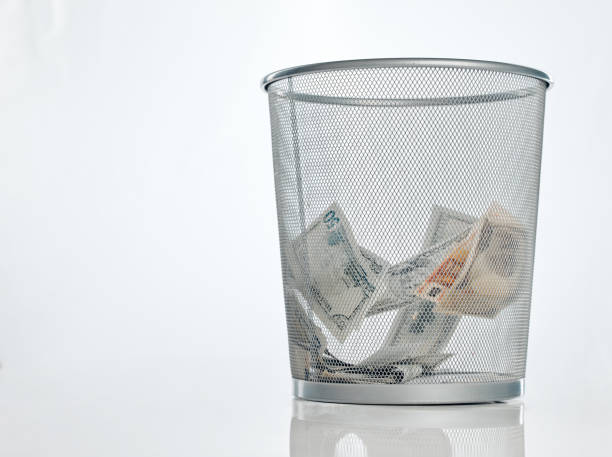 istock Studio shot of a trashcan filled with banknotes against a white background 1368090936