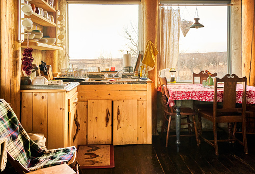 Kitchen and dining table inside of a rustic wood cabin in the countryside during the winter