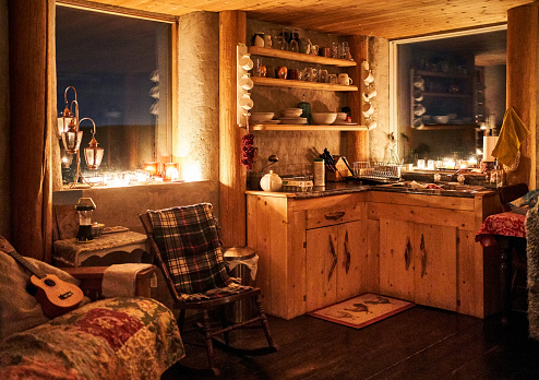 Interior of an eco cabin with small kitchen, chair and sofa at night