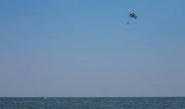 Photo of Parasailing is a popular type of outdoor activity at the sea. Parachute soars in the sky over the Sea with tourists