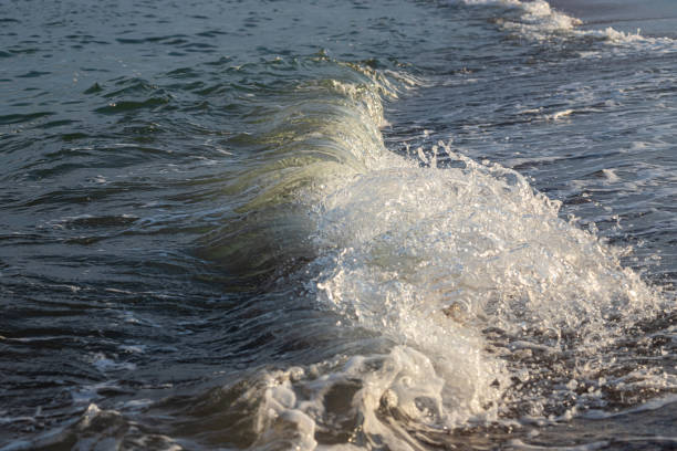 Sea waves crash against large rocks on the shore, forming large splashes..